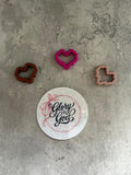 May include: Three pixelated heart-shaped stickers in brown, pink, and beige. A white sticker with a red ribbon and the text 'Glory to God' is in the center of the image.